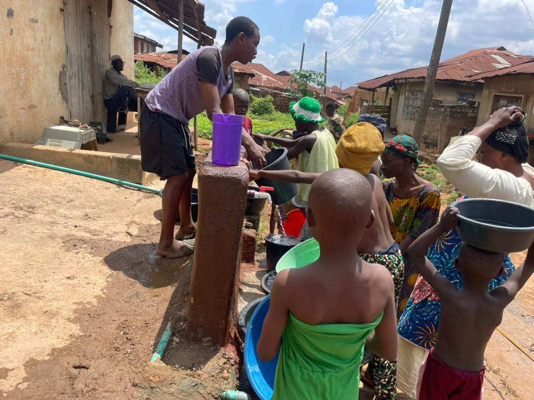 Women carrying basins of water on their heads in a queue