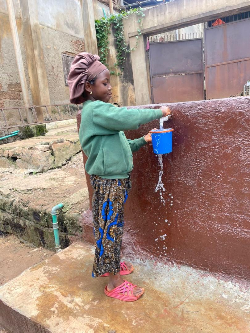 A young girl filling a blue cup from the tap