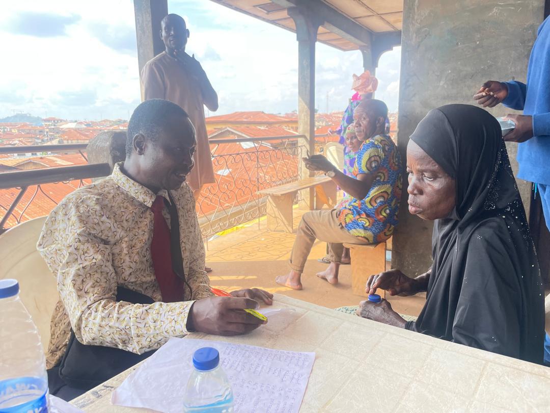 A volunteer in conversation with an elderly patient at the consultation table