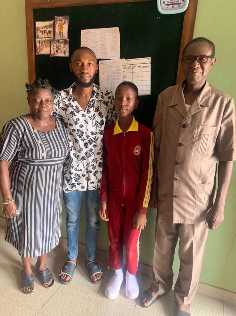 A foundation representative with a student and her family in a classroom